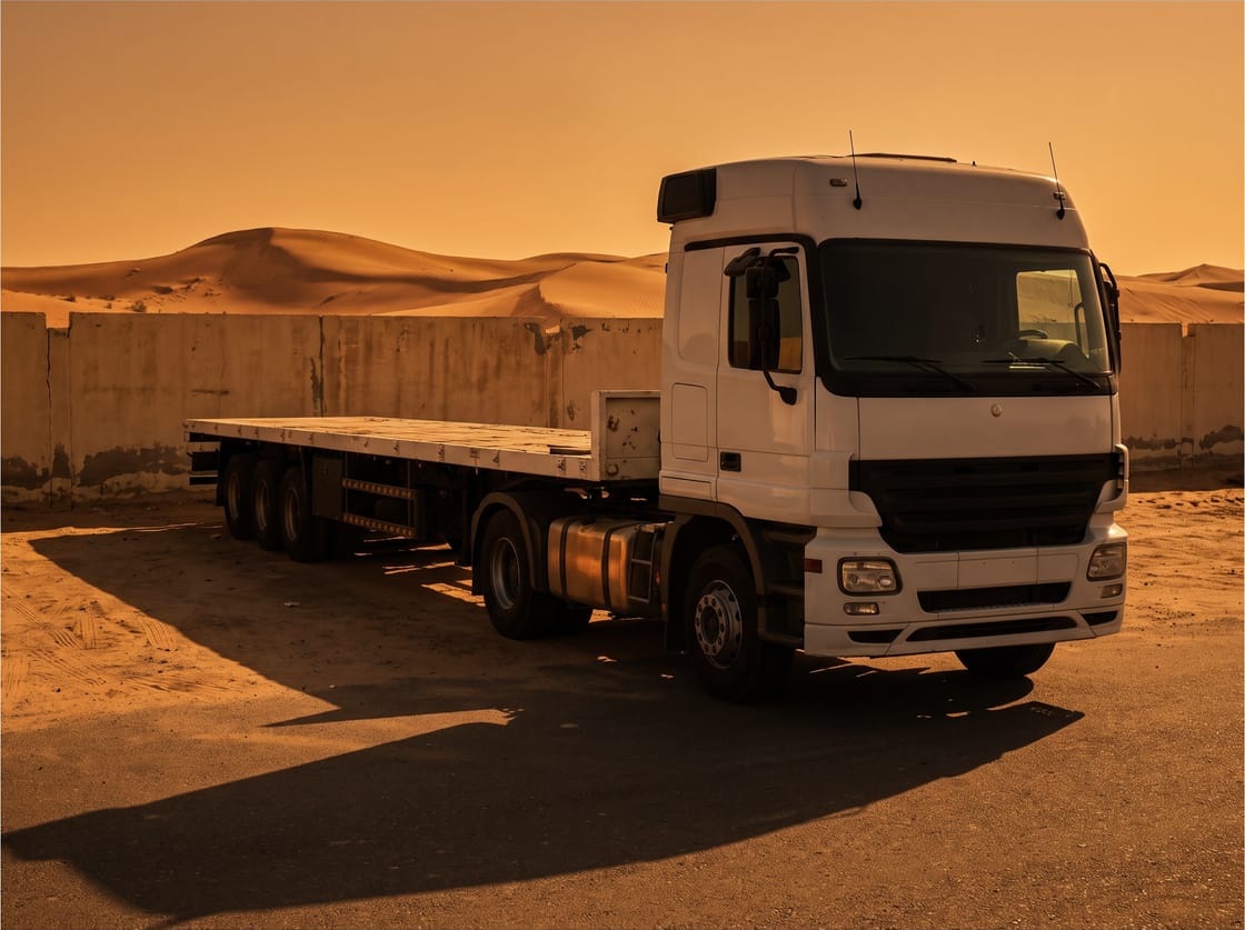 Empty flatbed trailer with clean deck coupled to a white tractor unit in a depot yard